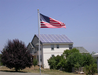 A flag flying in front of a house with solar panels on the roof.